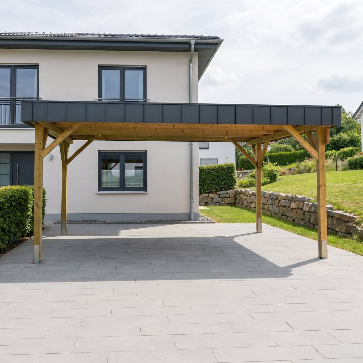 Doppelcarport Amecke Premium aus Holz mit anthrazitfarbener Dachblende auf einer breiten Einfahrt vor weißem Einfamilienhaus