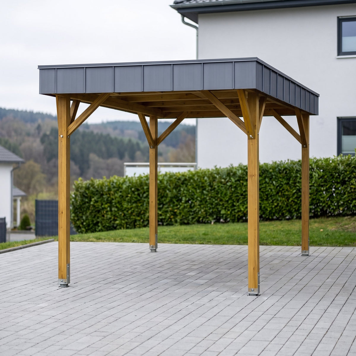 Frontansicht des Einzelcarports Arnsberg Premium aus Holz mit anthrazitfarbener Blende vor einer Hecke
