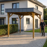 Mann steht neben dem Einzelcarport Arnsberg Premium aus Holz auf der Einfahrt